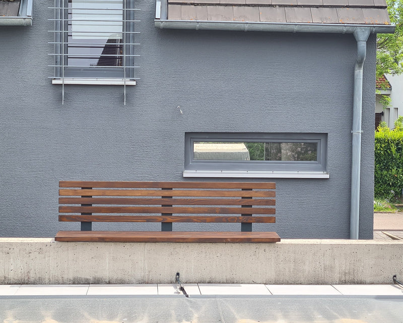 Gartenbank aus Stahl und Holz an einer Hauswand
